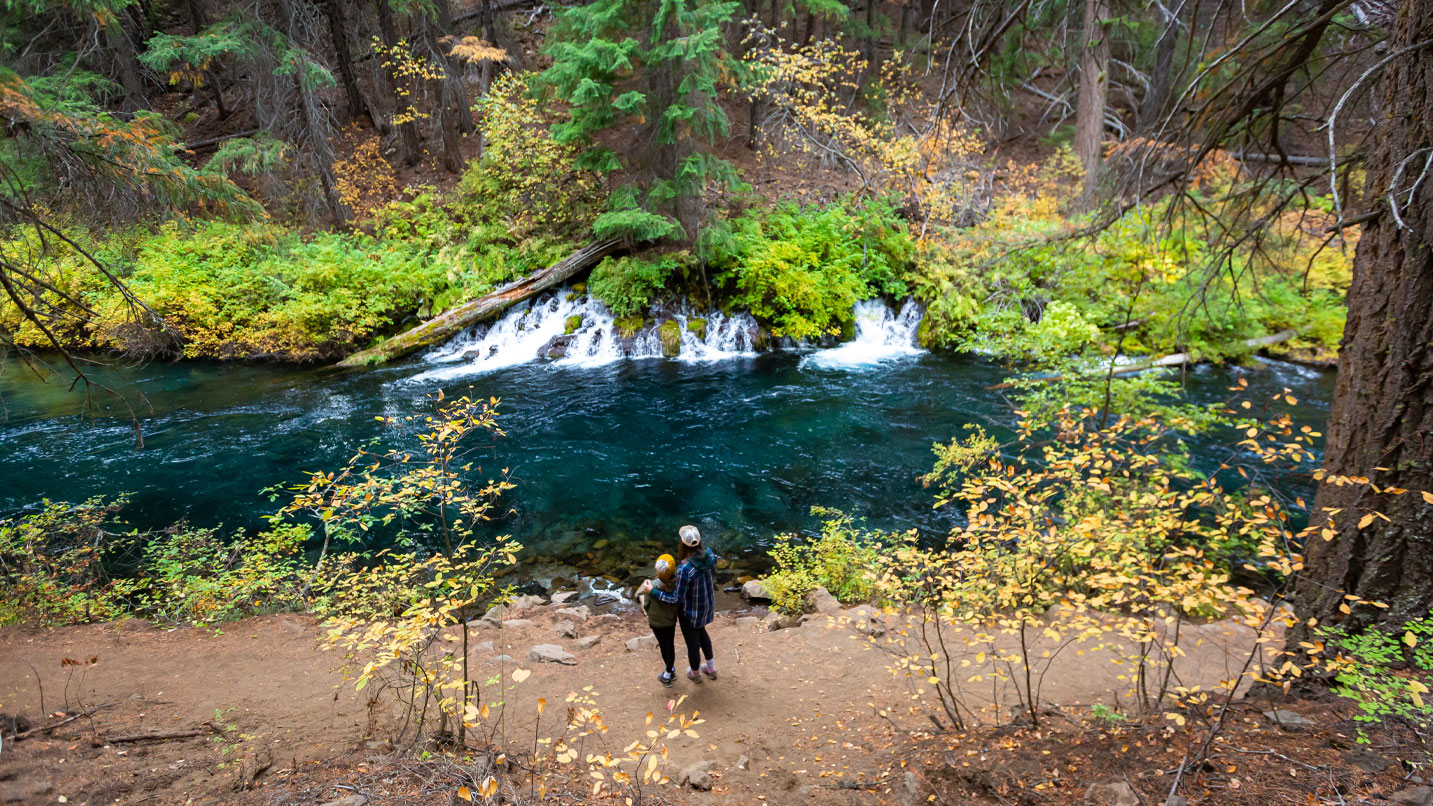 Two people overlooking a waterfall into a river.