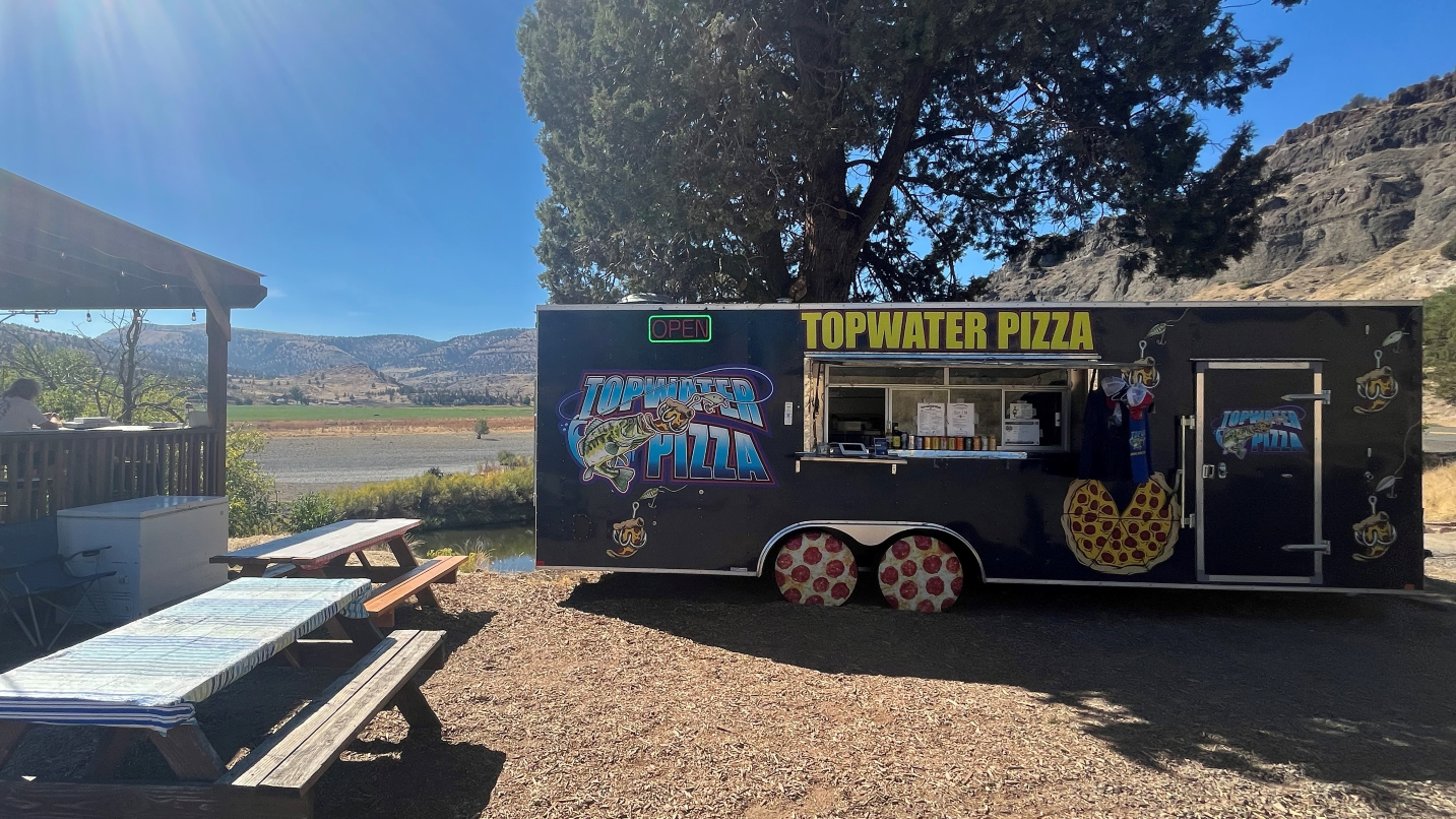 Food cart and picnic tables against mountains and river