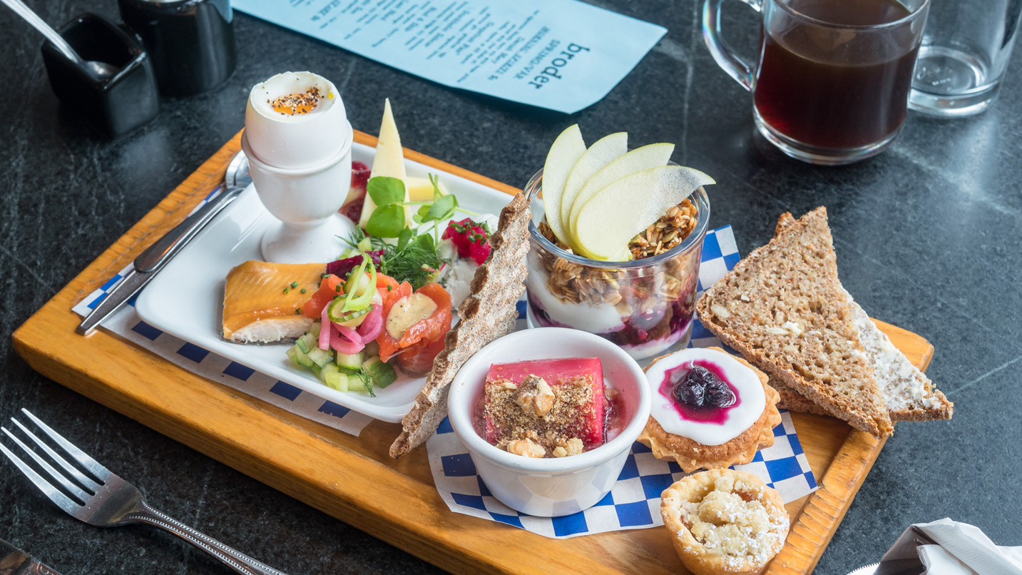 Wooden tray with toast, fruit, eggs and other breakfast items