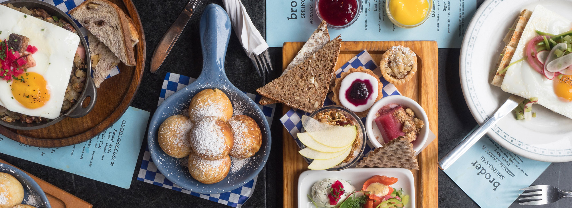 Overhead of several plates and trays of breakfast food