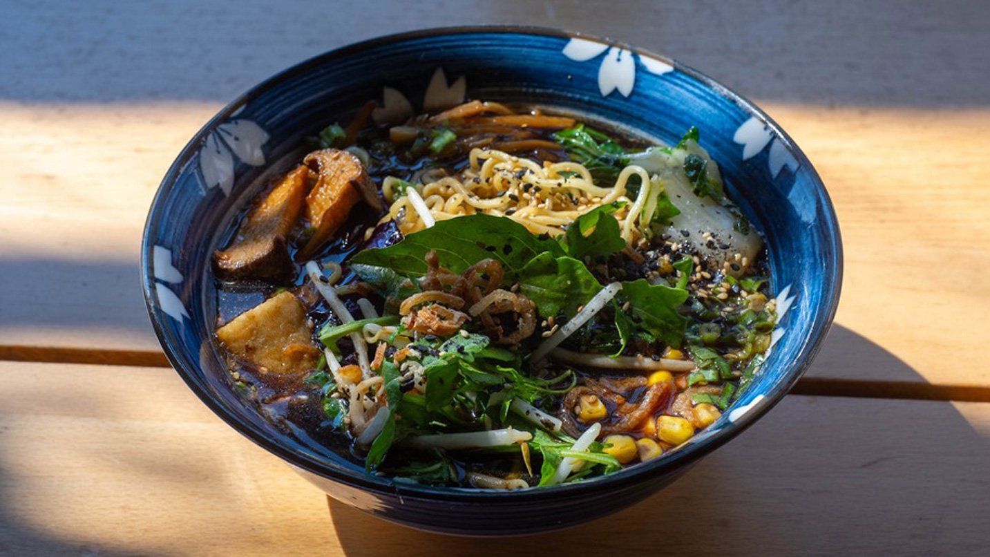 A bowl of ramen, topped with roasted coard, mushrooms, bok choy and bean sprouts.