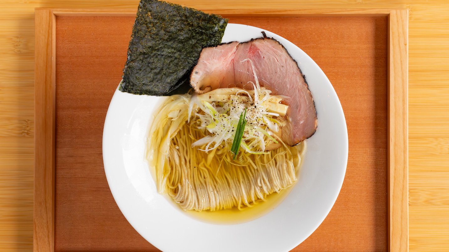 A bowl of ramen, with clear broth, pork and seaweed.