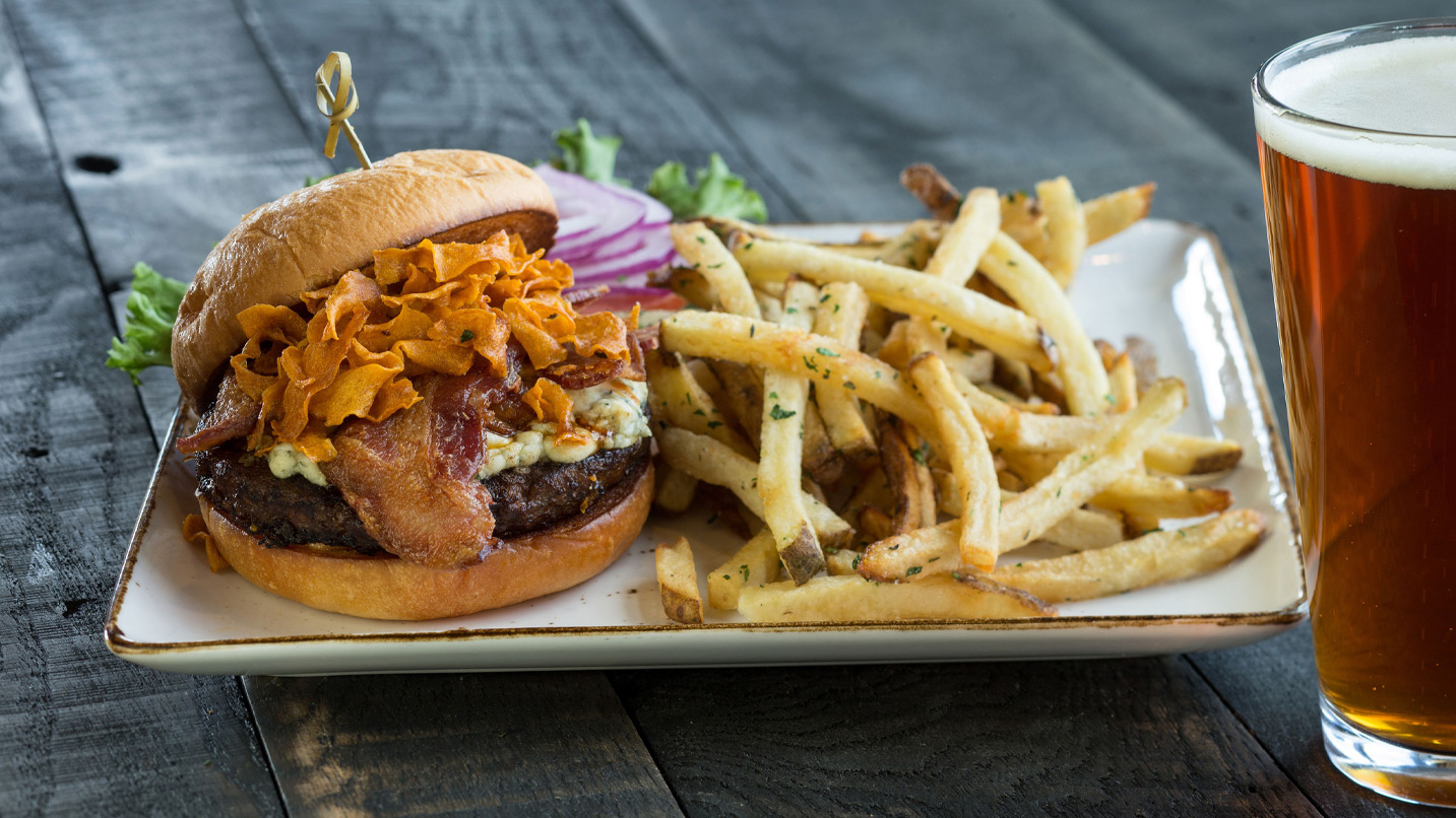 Hamburger, french fries and a pint of beer on a table.