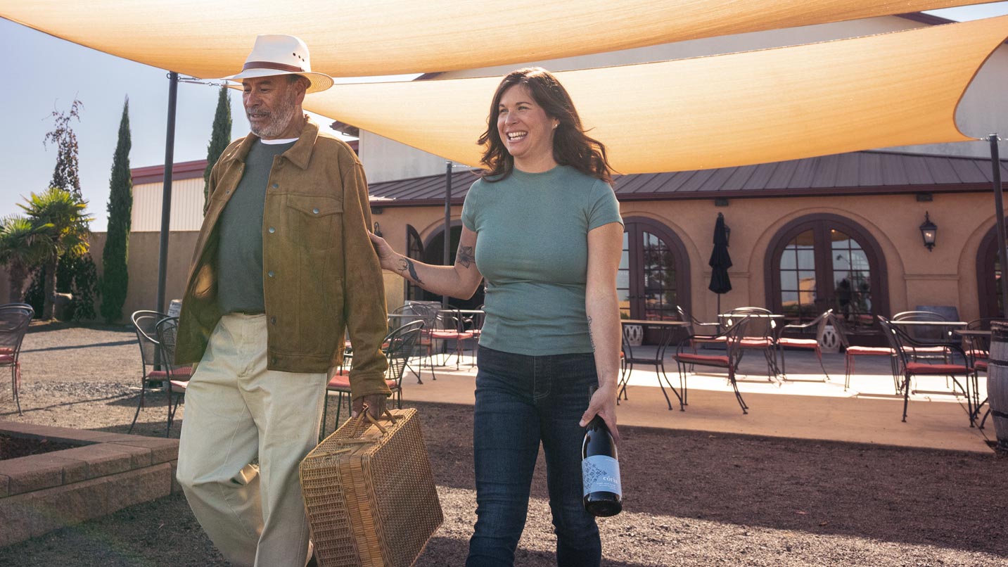 Aurora Cória and her father Luis Cória smiling and walking through the winery's outdoor patio.