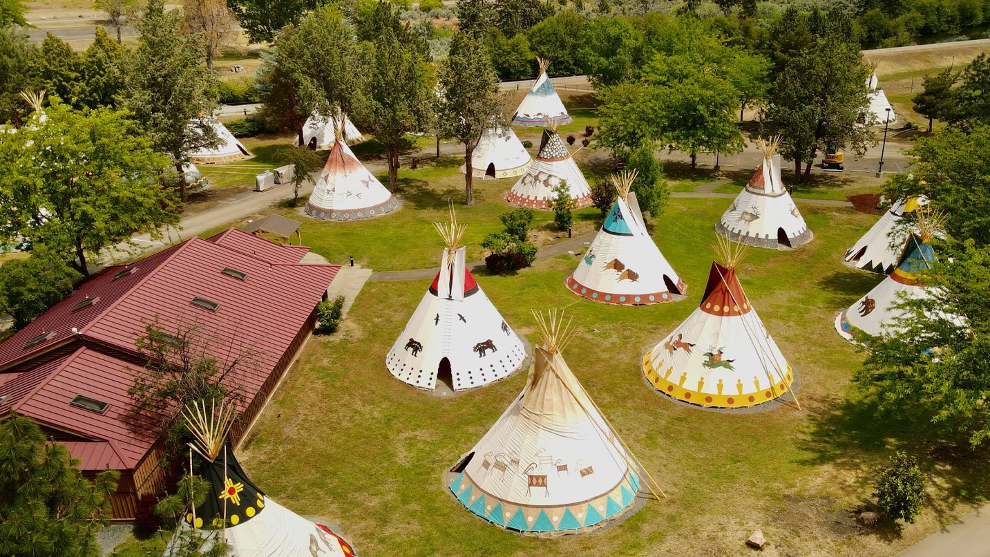 Teepee huts on a manicured resort lawn.
