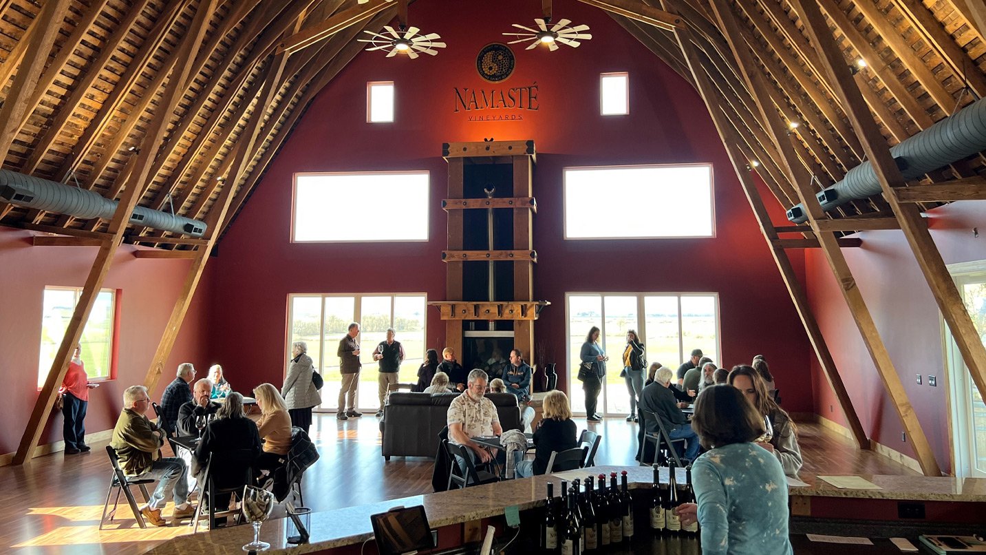 People drinking wine inside a barn-like structure.