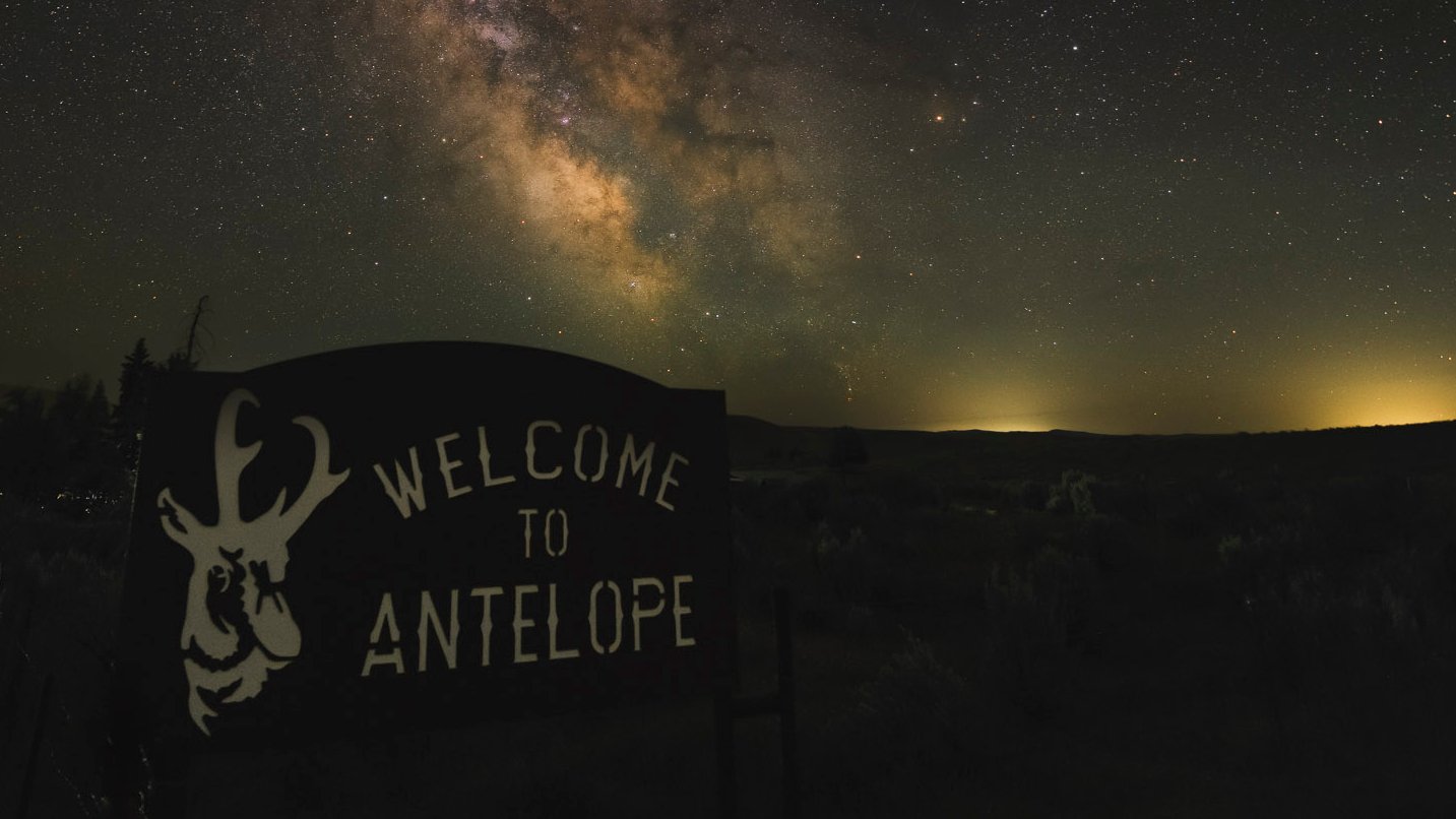 A "Welcome to Antelope" sign in the foreground against a starry night sky