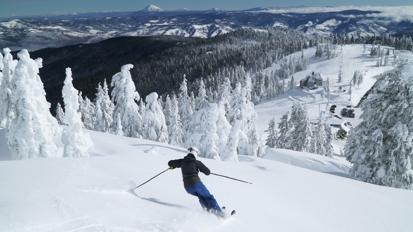 A single person skiing down the mountain, with views of a snowy landscape.