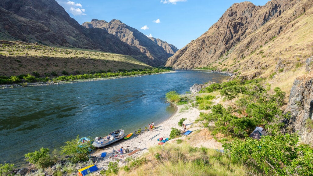 Tents and rafts alongside a river canyon.
