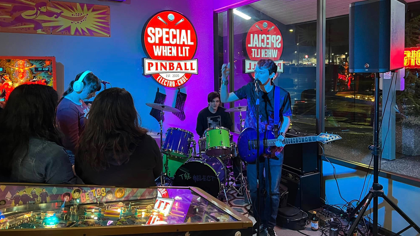 A live band plays inside a pinball arcade.