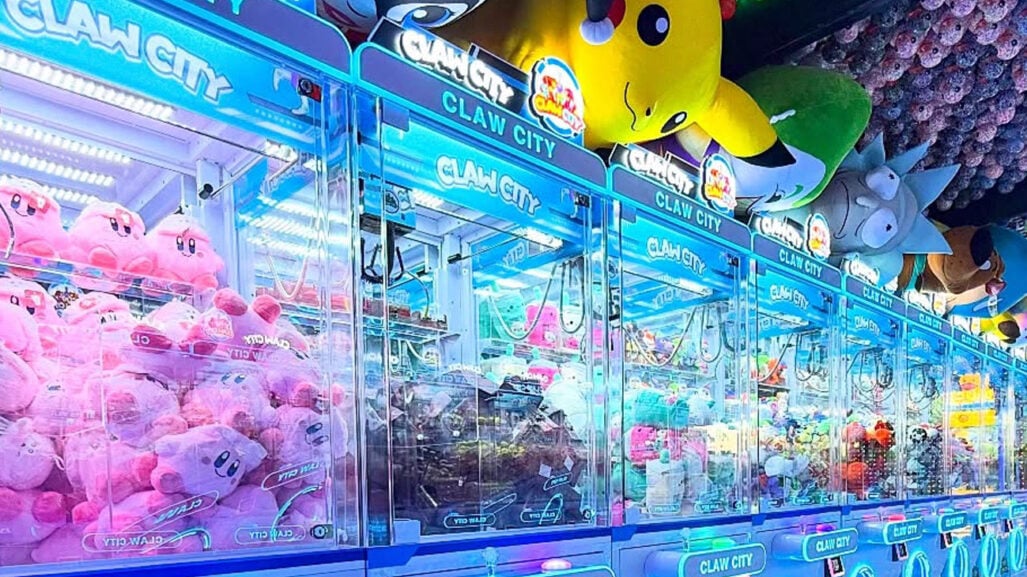 A line of claw machines in a colorful space.