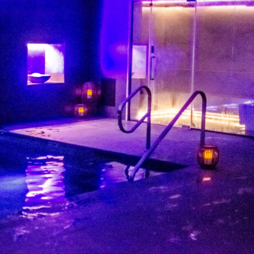 Purple light shines on pool and glass doors to sauna