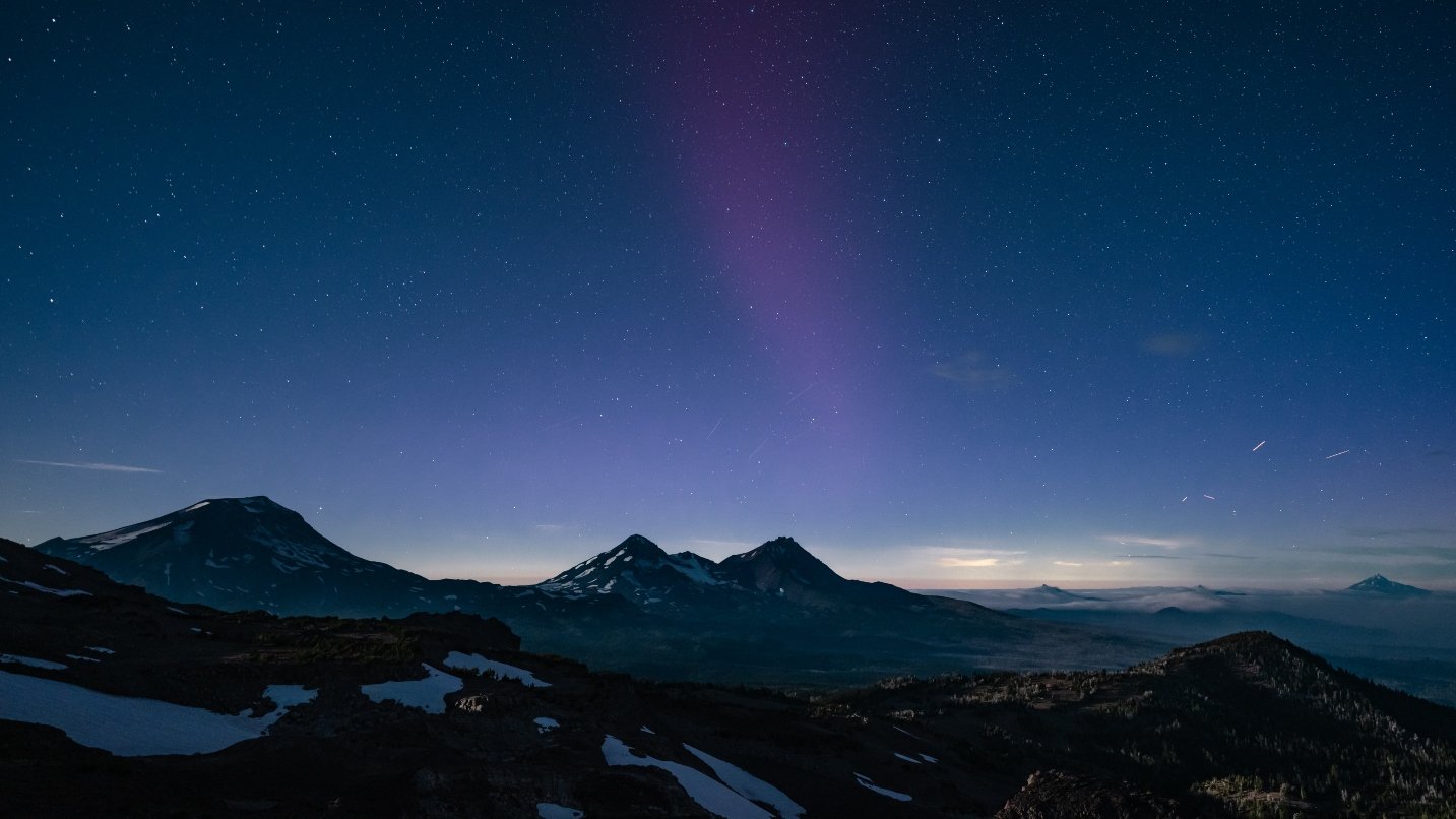 Dark blue night sky with stars over mountain range and a bit of snow