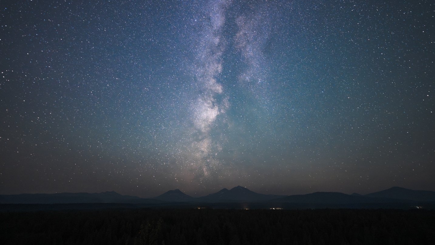 Dark blue night sky with Milky Way stars and mountain range in the background