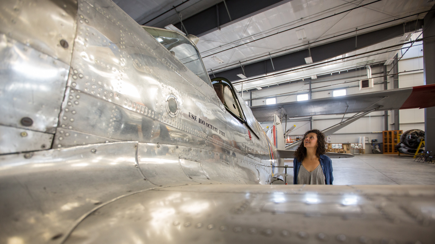 A woman looks at steel plane.