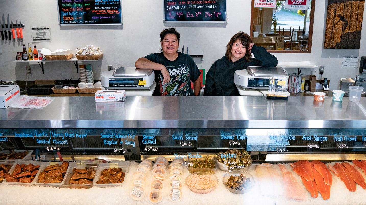 From left, owners Terrie and Kim Brigham stand in front of a display showcasing fresh-caught and dried fish filets.