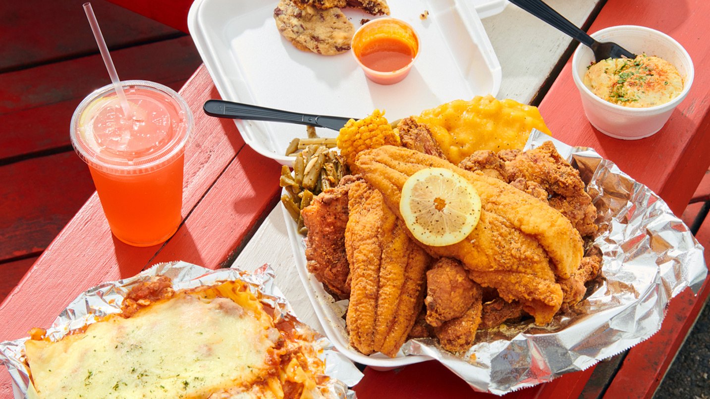 A plate loaded with classic soul food items, including fried catfish, mac and cheese, corn and green beans.