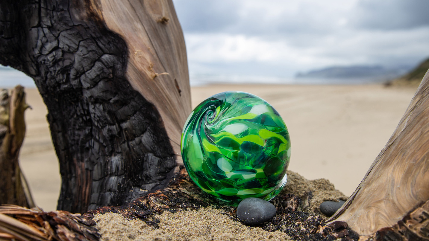 A green marbled glass float on a log on the beach of Lincoln City.