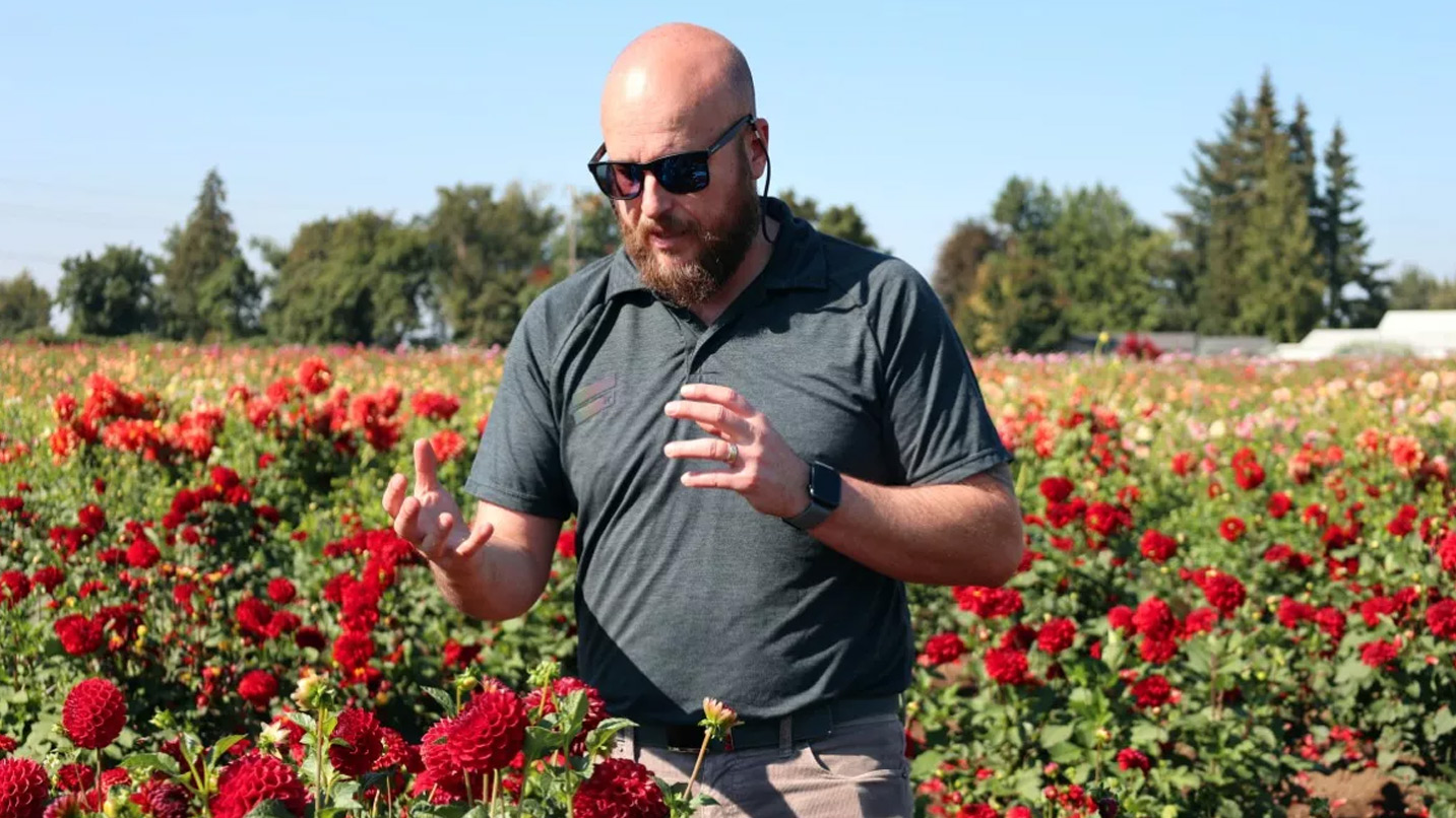 A person wears glasses in a field of flowers.