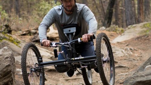 An adaptive mountain biker navigates an expert dirt trail.