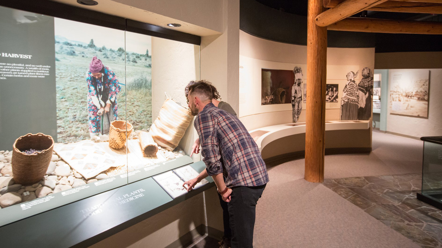 A person in a museum looks at traditional Native American baskets.