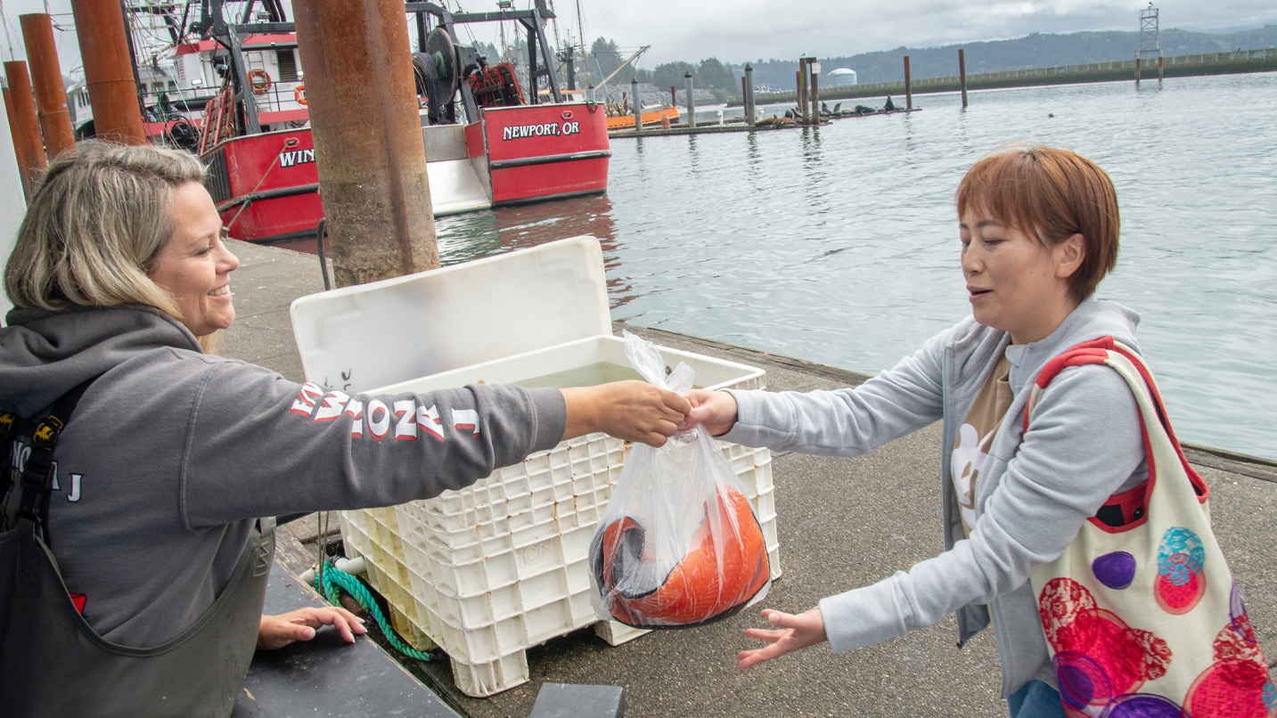 A person buys a bag of fresh fish off of a boat.