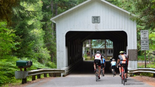 Cyclist biking through a covered bridge.