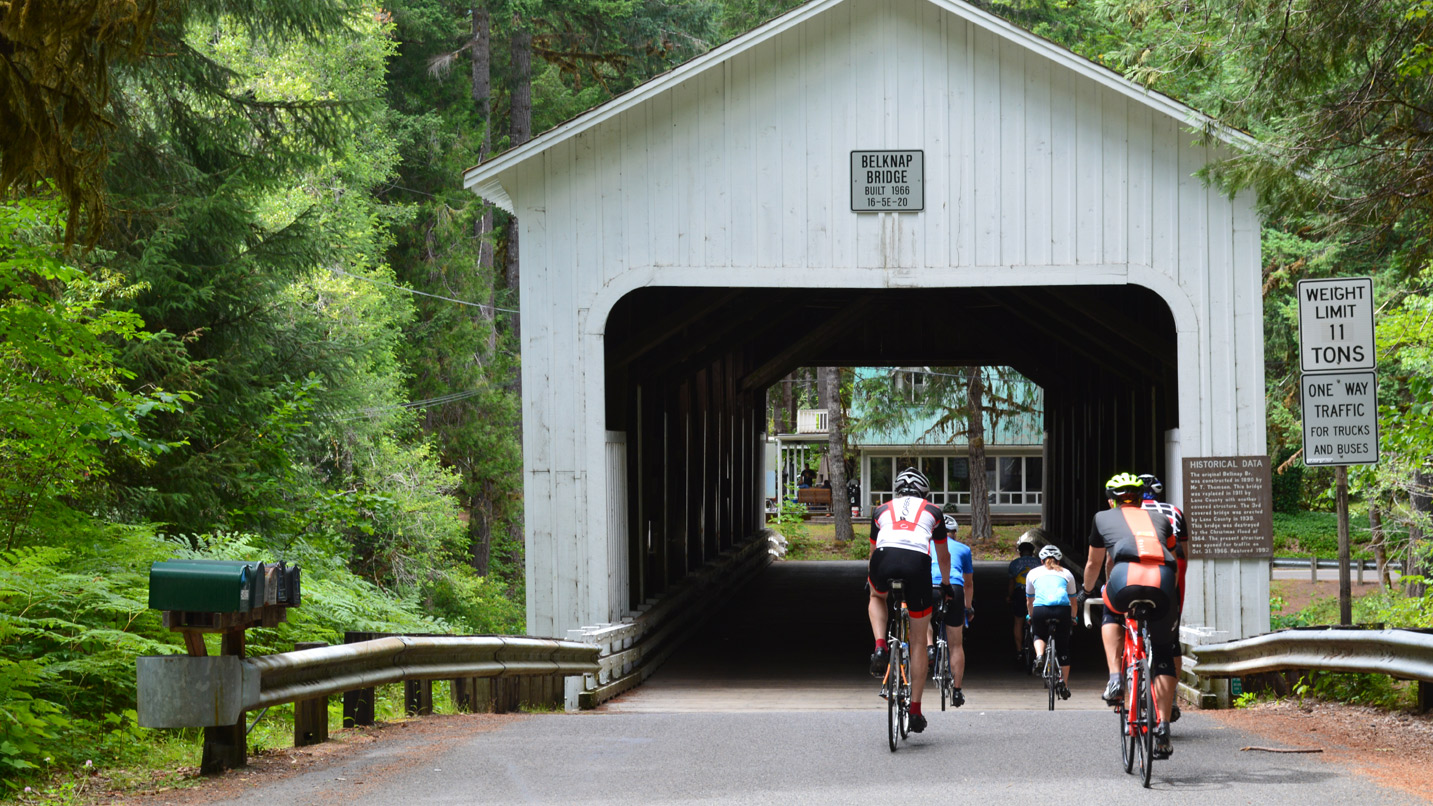 Cyclist biking through a covered bridge.