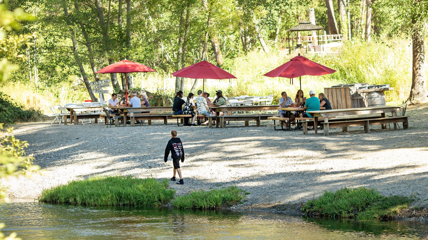 Picnic tables line a calm river.