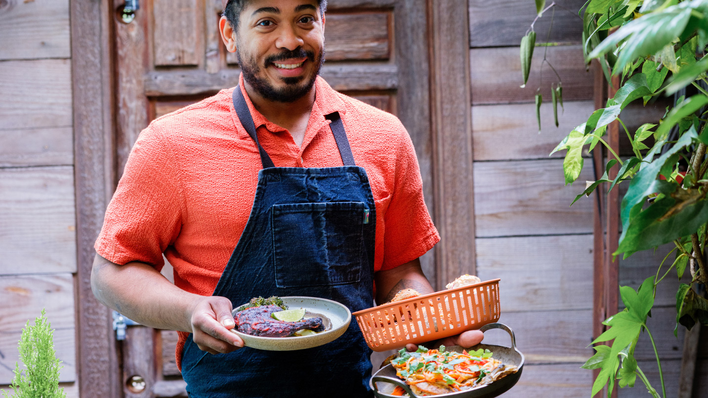 A smiling waiter holding several dishes.