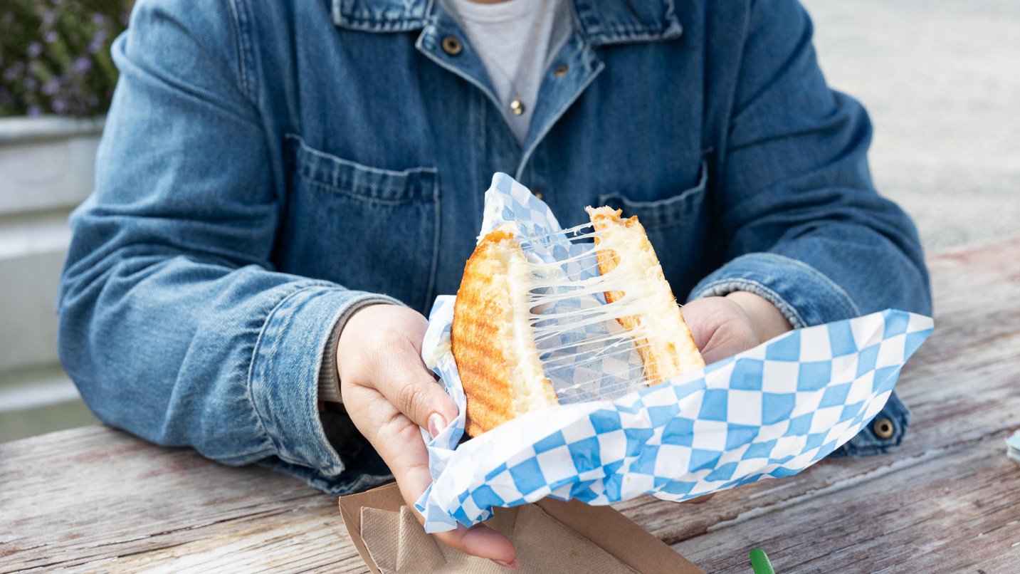 A person pulling apart a grilled cheese.