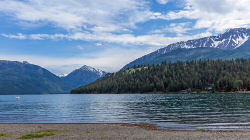 Wallowa Lake from the view of the shore. Mountains and trees are visible in the background.