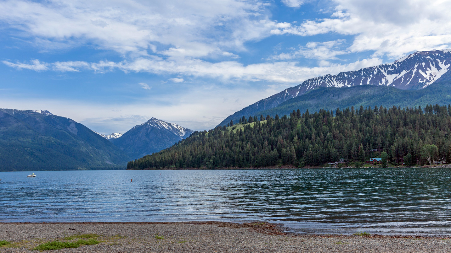 Wallowa Lake from the view of the shore. Mountains and trees are visible in the background.
