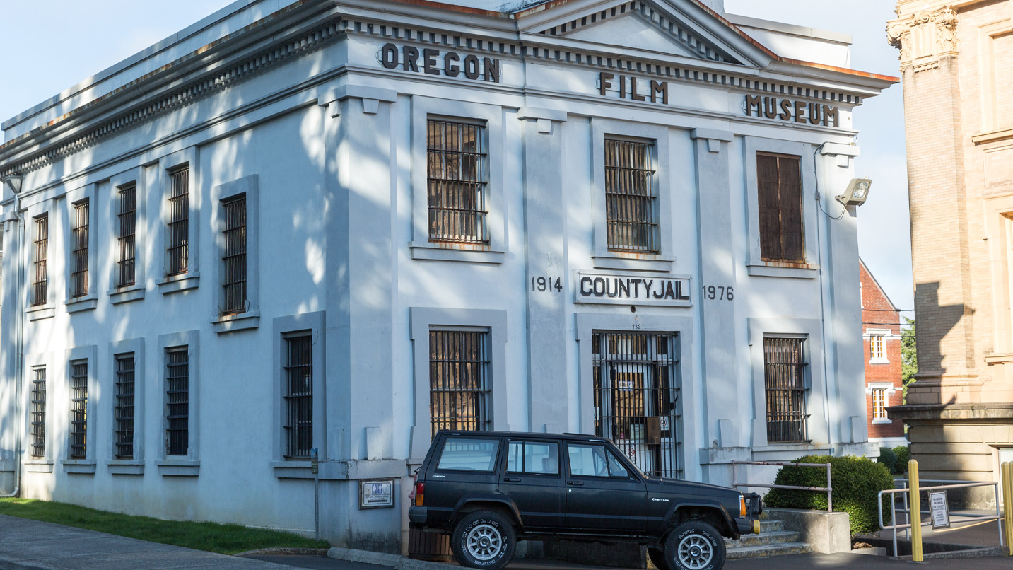 A view of an old county jail building, now with large letters that say Oregon Film Museum.