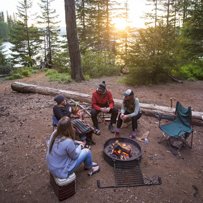 A family sits around a fire pit at sunset.