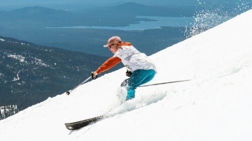 A skier descends a slope in perfect sunny spring conditions.