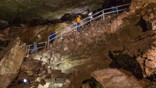People climbing stairs inside a cave formation.