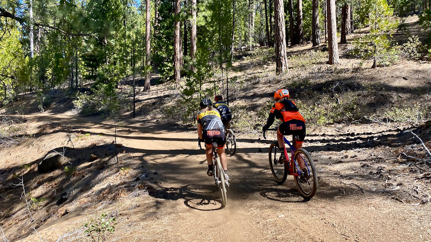 Women cycling on a dirt road in nature.