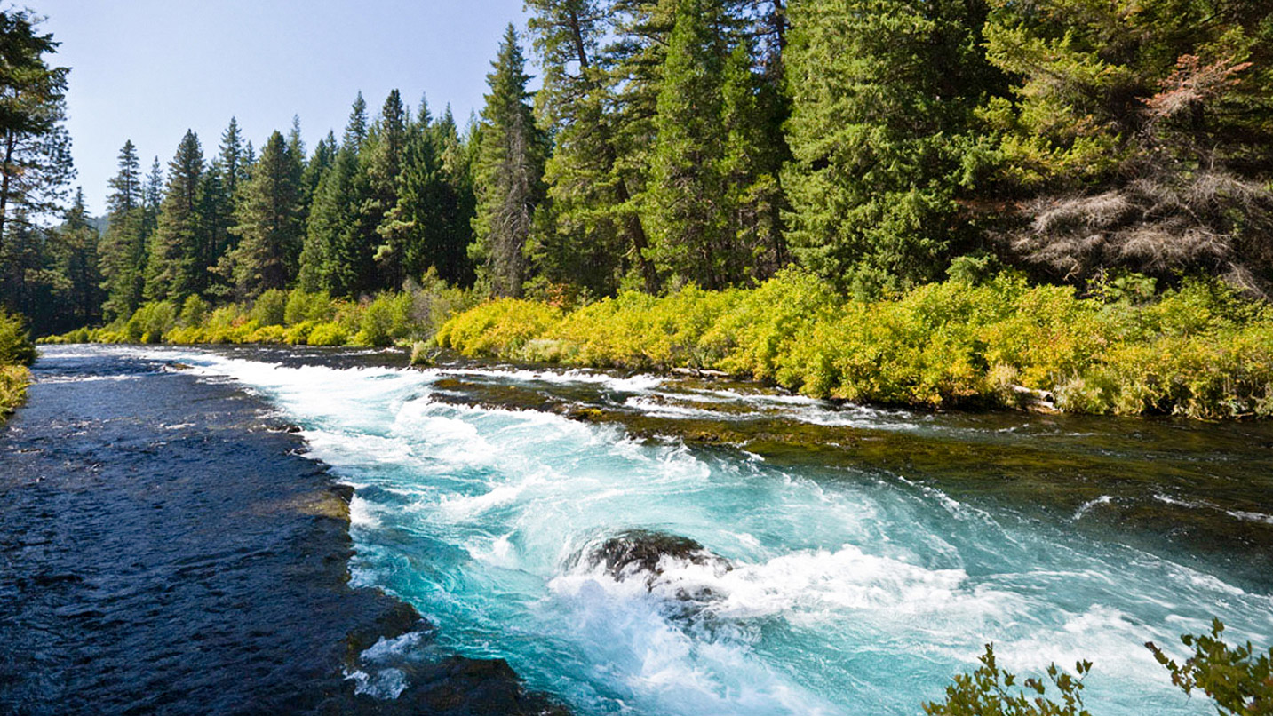 A strong current running down the middle of a wide river.