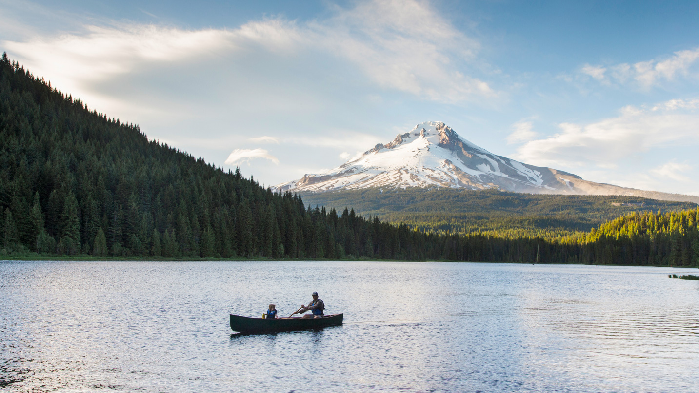 A canoe in a lake with a snow-capped mountain in the distance.