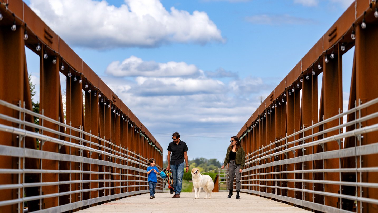 A family and dog walking across a footbridge.