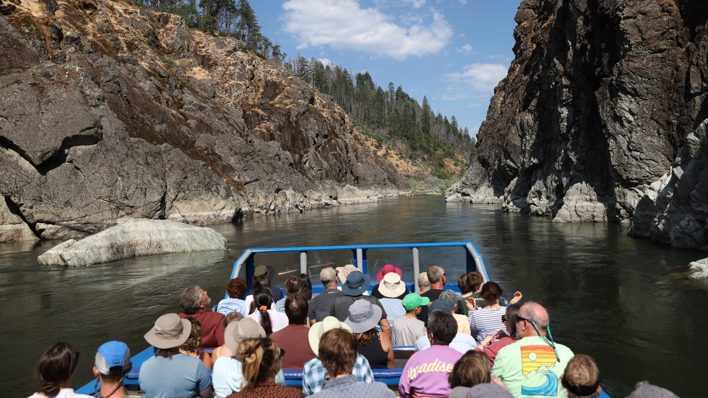 A jetboat travels through a scenic rive canyon.