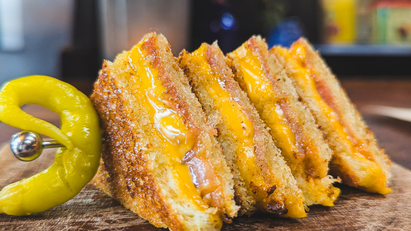Slices of a melted cheese and ham sandwich skewered together on a plate.