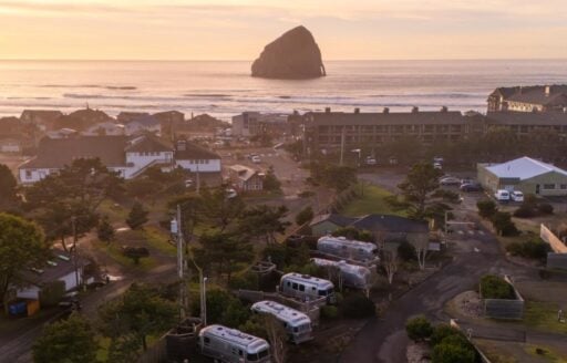 RV park with airstream trailers in the foreground with Oregon coast and large haystack rock in the background.
