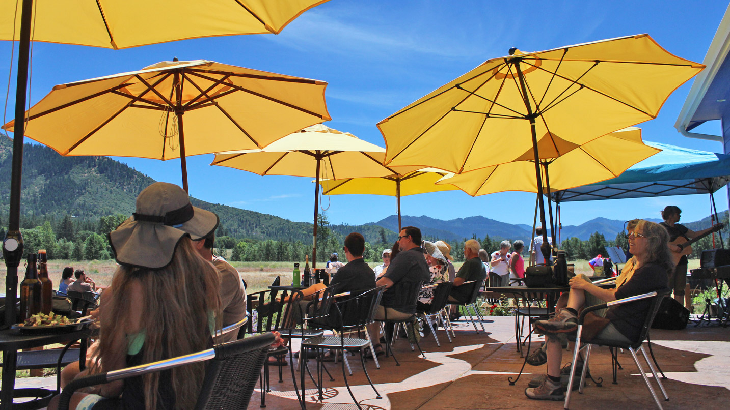 People sit on an outdoor deck shaded with yellow umbrellas.