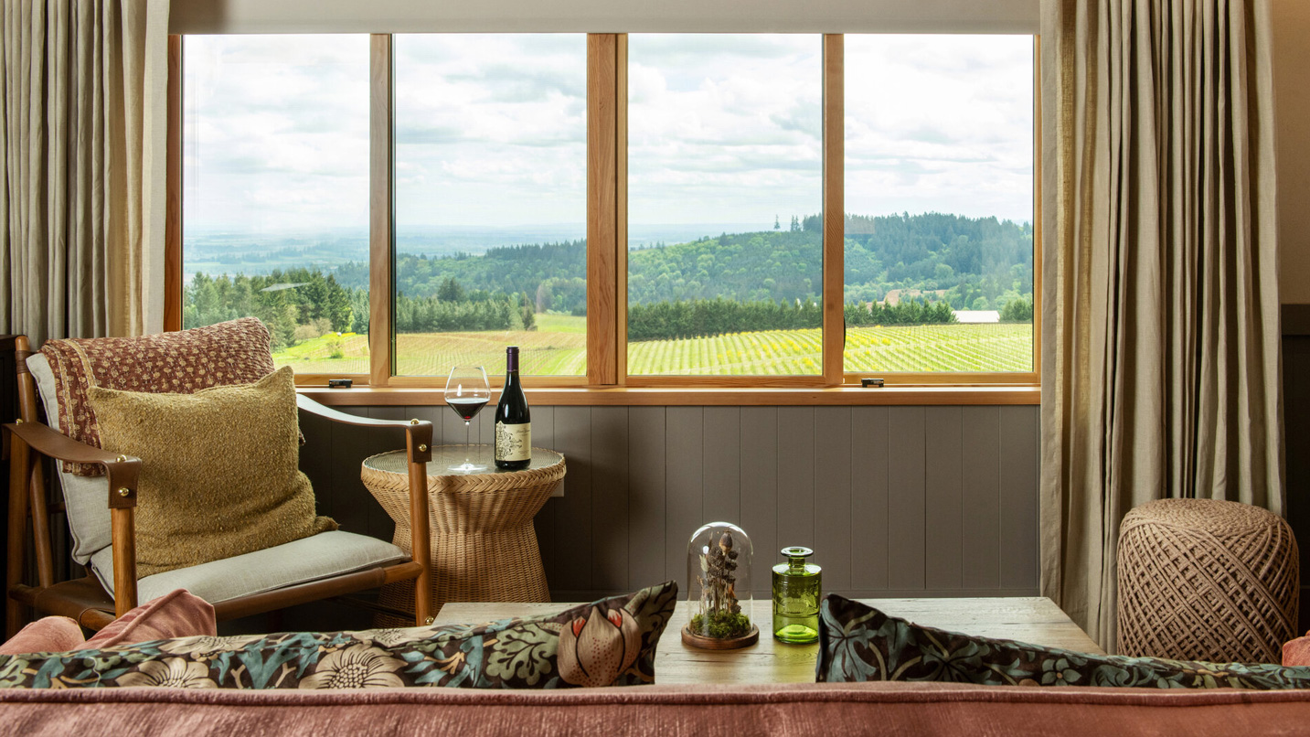 Interior hotel room with large windows overlooking a vineyard.