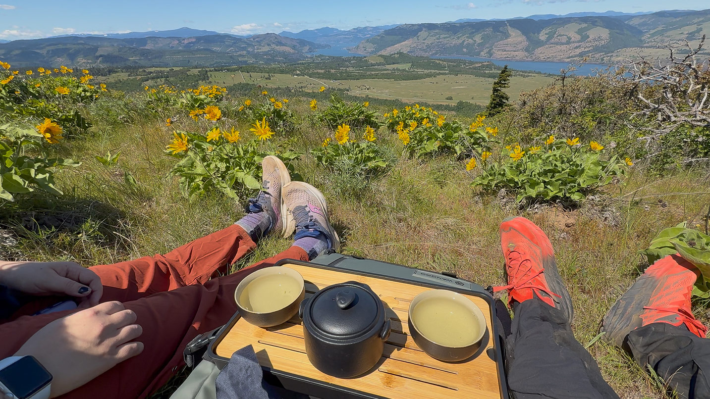 Two people sitting in a field of wildflowers with tea.