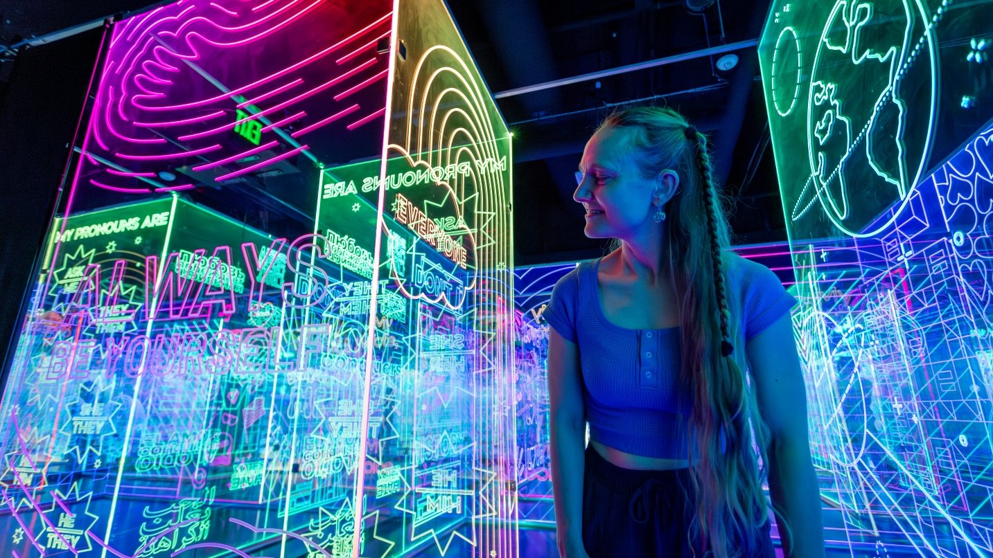 Woman smiles with colorful neon lights and signs in background