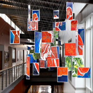 Various-sized pieces of art hang together from a ceiling.