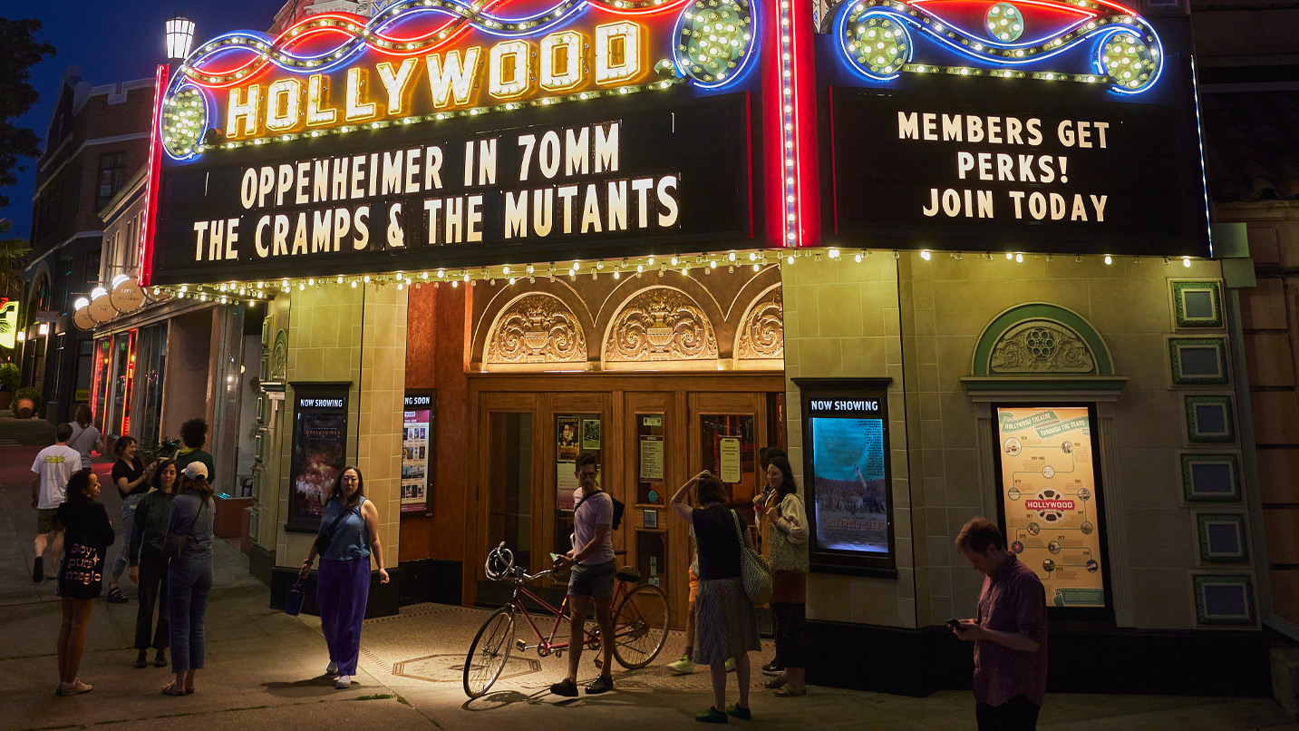 Marquee sign of the Hollywood theater, folks outside the theater mingling.